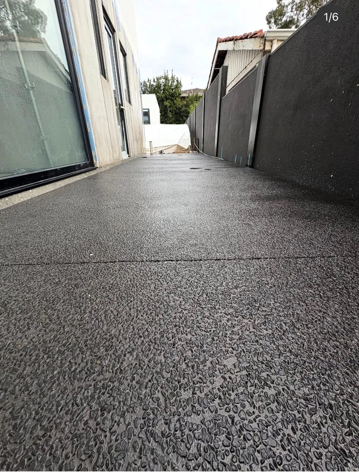 Exposed aggregate path running between two rendered homes, the washed stone surface leading away to a bright sky