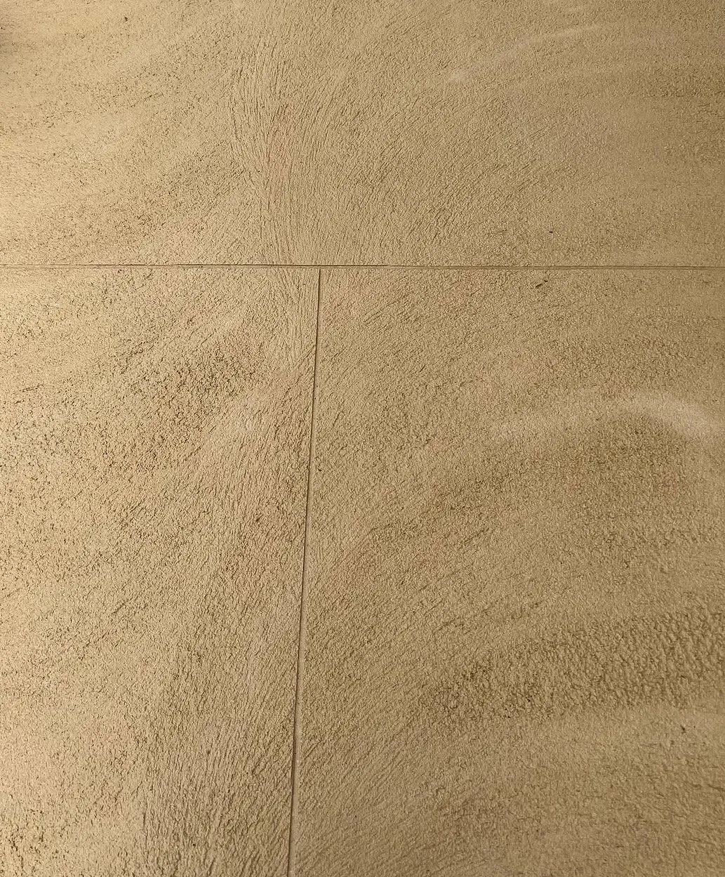 Close view of honey-toned liquid limestone with a brushed swirl texture and a fine saw-cut control joint