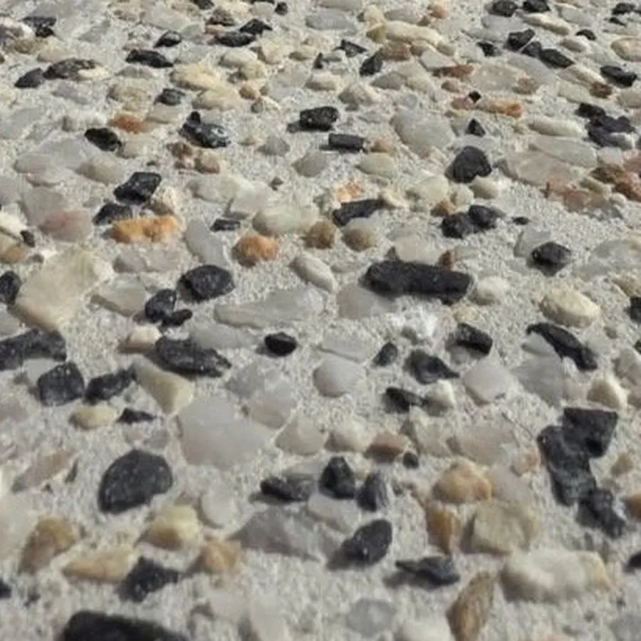Close view of exposed aggregate: whole rounded pebbles in cream, honey and black sitting proud of the cement around them