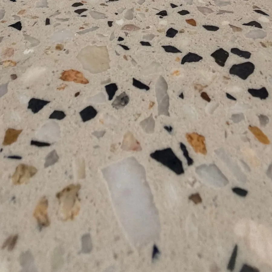 Close view of honed concrete: stones cut flat and level with the cream cement, black and pale fragments reading like terrazzo